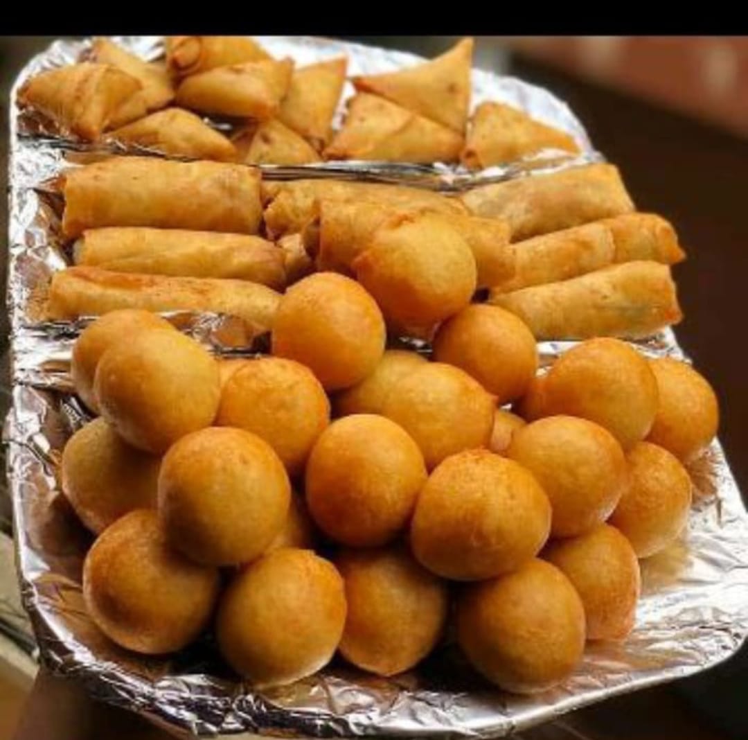 Tray of freshly fried puff puff, samosa and spring rolls