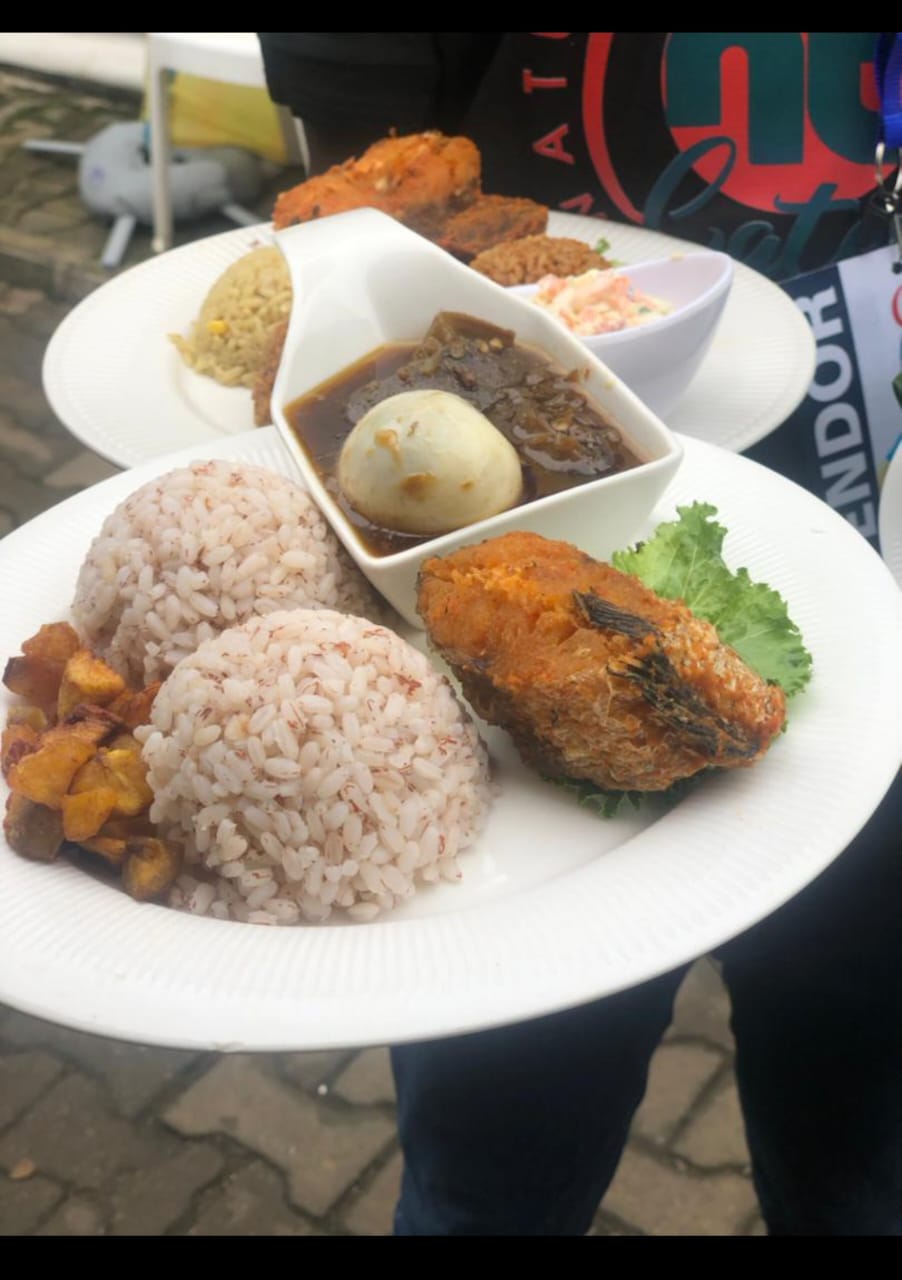 Ofada rice plate with fried fish, stew and plantain at a Lagos event